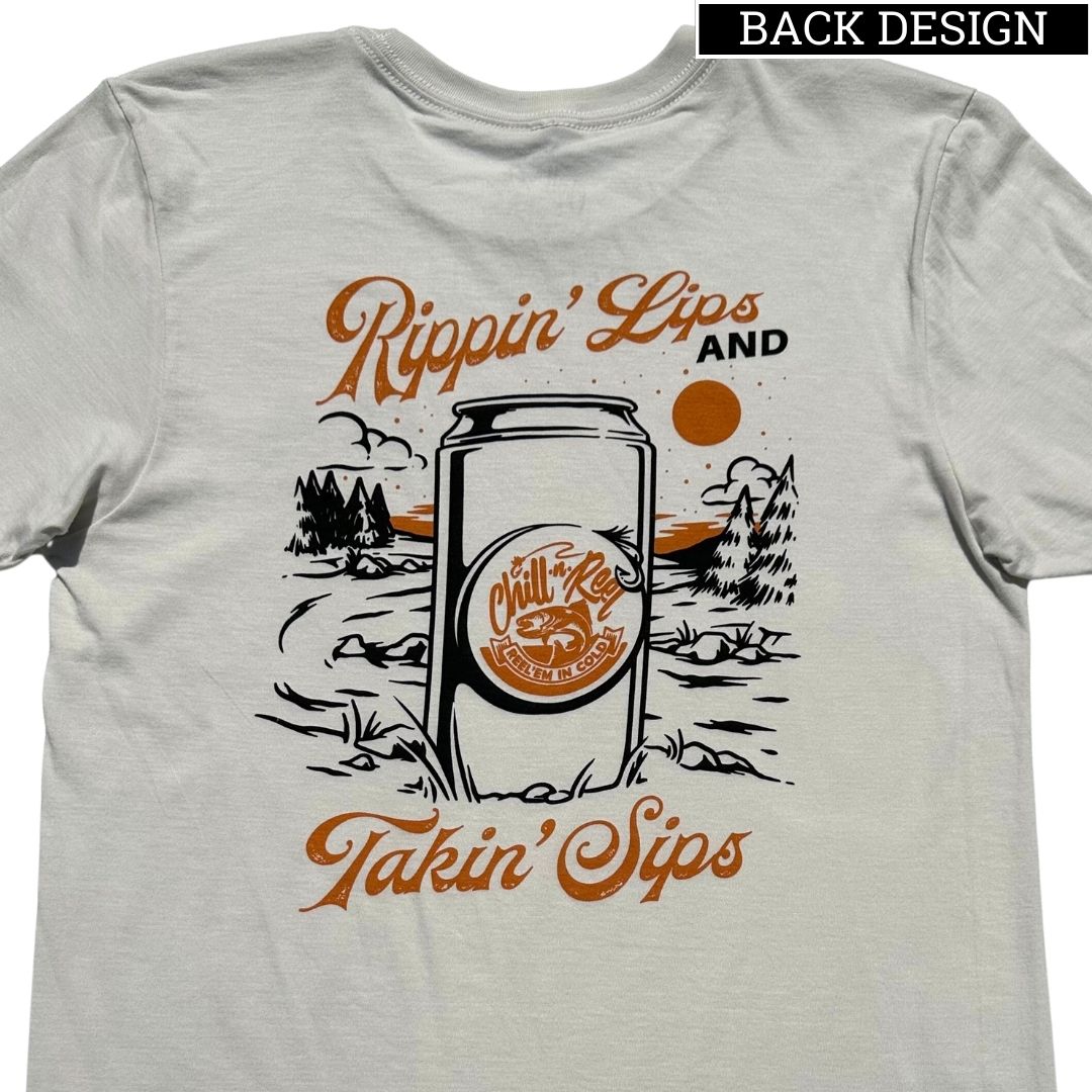 A Chill-N-Reel Soft Short Sleeve T-shirt - Rippin Sippin LANDSCAPE with Chill-N-Reel graphic on the back depicting a canned beverage in the foreground. The can features the text "Chill" and "Take it Easy," surrounded by an outdoor scene with trees, hills, and an orange sun. Made from 100% cotton, the t-shirt reads "Rippin' Lips and Takin' Sips".