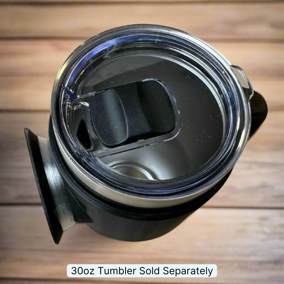 A close-up of a transparent tumbler lid featuring a sliding closure, placed on a wooden surface. The Chill-N-Reel® Tumbler Handle is shown connected to the dark handle. Text below states, "30oz Tumbler Sold Separately.