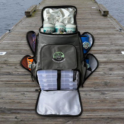 A gray Fishing Tackle Backpack with Cooler Top by Chill-N-Reel® sits open on a wooden dock, showing off its tackle storage and packed items like plastic boxes and containers. Adorned with patches featuring the "Gill Gear" logo, this versatile bag also includes a cooler top as the dock extends into the water.