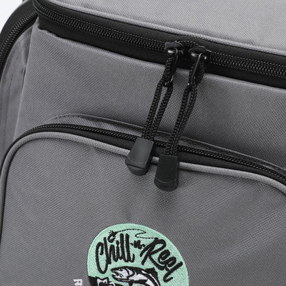 Close-up of the Chill-N-Reel® Fishing Tackle Backpack with Cooler Top, featuring black zippers. The front pocket showcases an embroidered patch with a fish and the words "Chill Reel" in stylized lettering, ideal for those who appreciate efficient tackle storage on their fishing adventures.