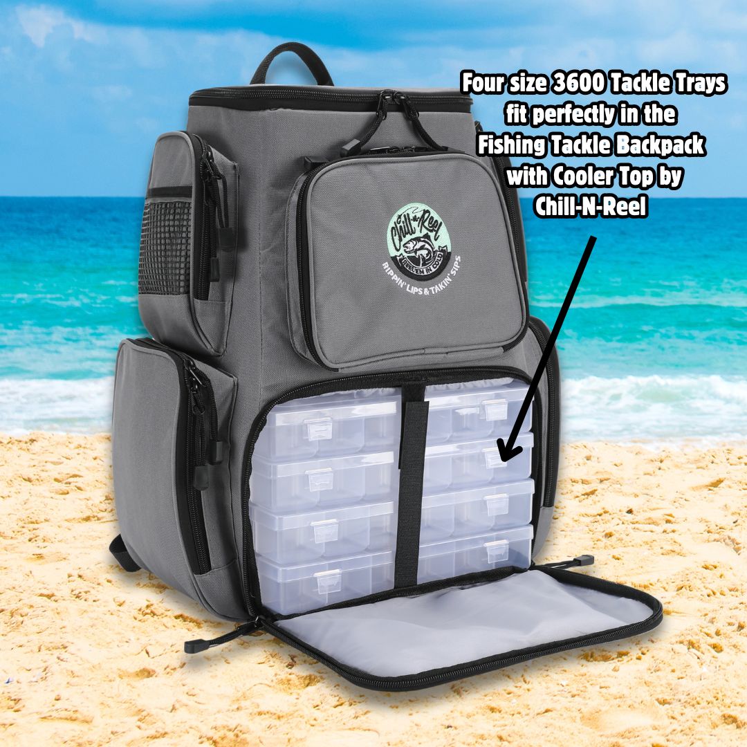 A Chill-N-Reel® fishing tackle box set with adjustable dividers and a visible logo is placed on a sandy beach, displaying its versatile compartments. It includes four size 3600 trays meticulously arranged in an open compartment against the backdrop of turquoise ocean waves, providing optimal storage for fishing gear.