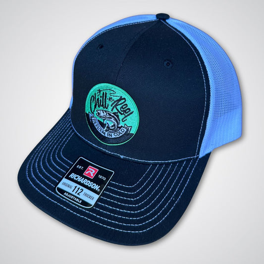 The Chill-N-Reel Trucker Hat by Chill-N-Reel is a black and white mesh cap featuring a green circular patch with a fish, white stitching, and a "Richardson 112" sticker—ideal for fishing adventures.